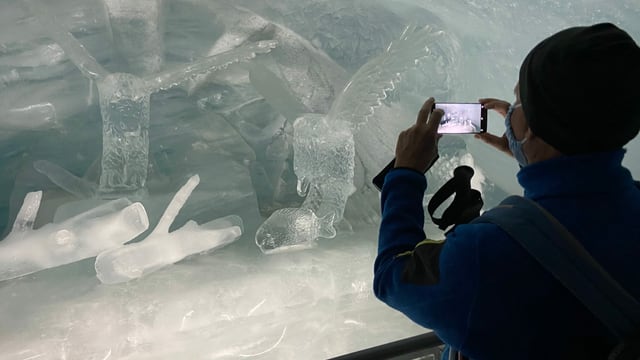 Eine Person fotografiert eine Eisskulptur Eine Person fotografiert eine Eisskulptur