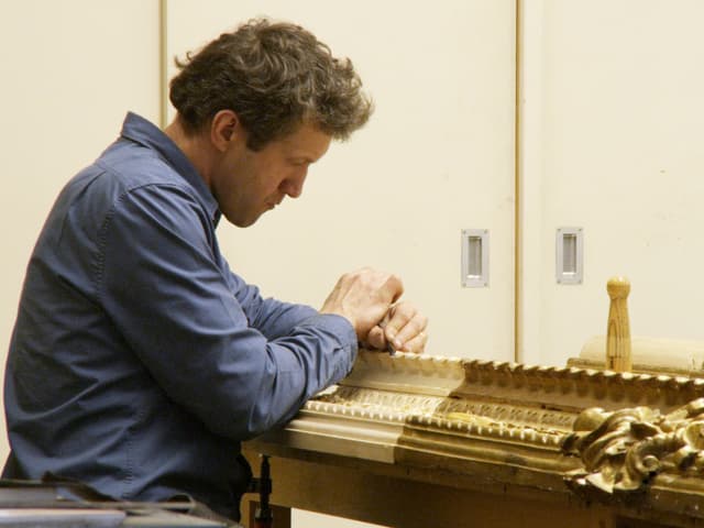 Ein Mitarbeiter der National Gallery schnitzt an einem goldenen Rahmen. Ein Mitarbeiter der National Gallery schnitzt an einem goldenen Rahmen.