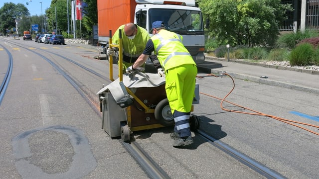 Zwei Arbeiter schleifen mit einer Maschine an einem Gleis. Zwei Arbeiter schleifen mit einer Maschine an einem Gleis.