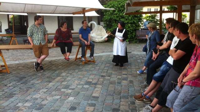 Eine Zeitfrau spielt eine historische Szene auf dem Fischmarktplatz in Arbon vor Publikum. Eine Zeitfrau spielt eine historische Szene auf dem Fischmarktplatz in Arbon vor Publikum.