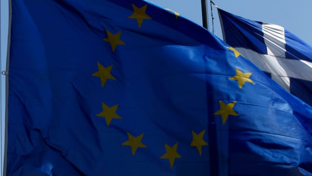 Eine EU-Flagge überdeckt eine Griechenland-Flagge. Eine EU-Flagge überdeckt eine Griechenland-Flagge.