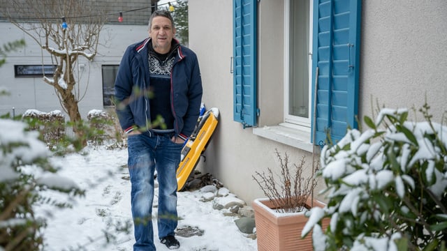 Ein Mann steht in einem Garten, im Hintergrund ist ein Schlitten zu erkennen. Ein Mann steht in einem Garten, im Hintergrund ist ein Schlitten zu erkennen.