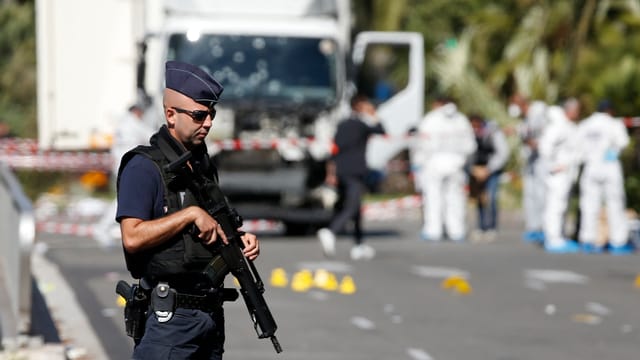Polizist mit Maschinengewehr vor Lastwagen in Nizza Polizist mit Maschinengewehr vor Lastwagen in Nizza