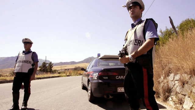 zwei Carabinieri stehen auf einer italienischen Landstrasse und halten Ausschau zwei Carabinieri stehen auf einer italienischen Landstrasse und halten Ausschau