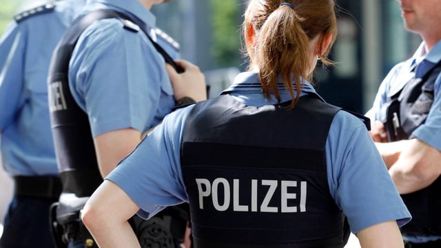 Mehrere Polizisten stehen mit dem Rücken zur Kamera Mehrere Polizisten stehen mit dem Rücken zur Kamera