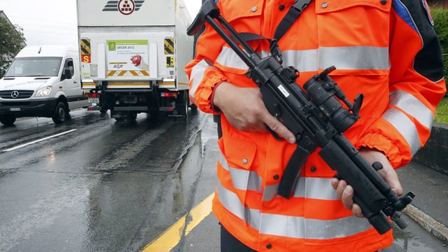 Ein Polizist steht während einer Fahndung mit seiner Waffen am Strassenrand. Ein Polizist steht während einer Fahndung mit seiner Waffen am Strassenrand.