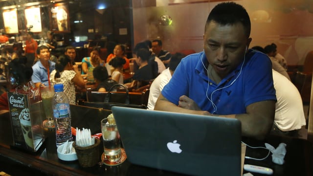 Ein Vietnamese sitzt in einem Restaurant in Hanoi vor einem Laptopp und surft im Internet. Ein Vietnamese sitzt in einem Restaurant in Hanoi vor einem Laptopp und surft im Internet.