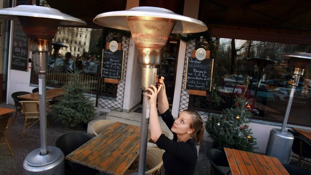 Angestellte bedient Heizpilz in deutschem Restaurant Angestellte bedient Heizpilz in deutschem Restaurant