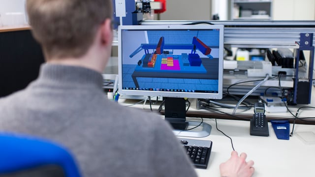 Aufnahme von hinten: Mann sitzt an Computer auf Bildschirm komplexe technische Zeichnungen Aufnahme von hinten: Mann sitzt an Computer auf Bildschirm komplexe technische Zeichnungen