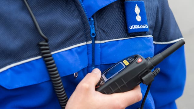 Ein Polizist hält ein Funkgerät in der Hand. Ein Polizist hält ein Funkgerät in der Hand.