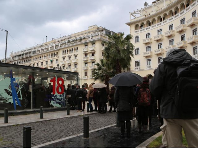 Blick auf einen Platz in Thessalonik. Menschen stehen vor einem Tickethäuschen an. Blick auf einen Platz in Thessalonik. Menschen stehen vor einem Tickethäuschen an.