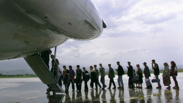 Eine Gruppe steht Schlange, um in ein Flugzeug zu steigen. Eine Gruppe steht Schlange, um in ein Flugzeug zu steigen.