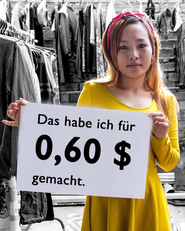 Eine Arbeiterin hält ein Schild mit der Aufschrift: Das habe ich für 0.60 Dollar gemacht. Eine Arbeiterin hält ein Schild mit der Aufschrift: Das habe ich für 0.60 Dollar gemacht.