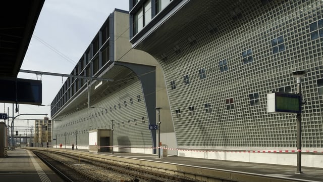 Die Fassade eines neuen Gebäudes blickt über die Gleise eines Bahnhofes.