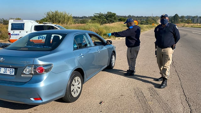 Zwei Polizisten kontrollieren ein blaues Auto. Zwei Polizisten kontrollieren ein blaues Auto.