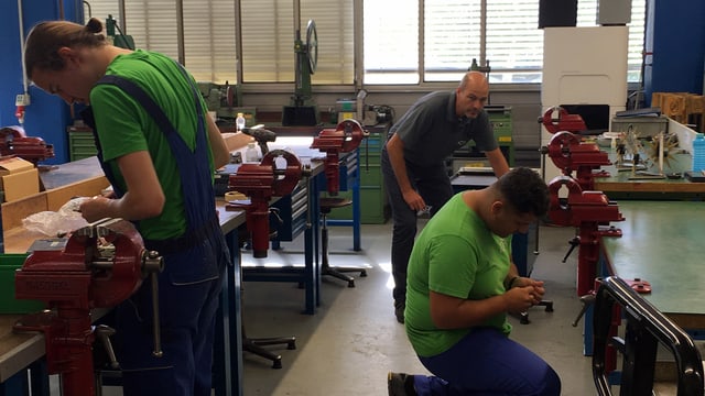 Blick in eine Werkstatt - zwei Lehrlinge sind am Arbeiten. Ein Lehrmeister schaut. Blick in eine Werkstatt - zwei Lehrlinge sind am Arbeiten. Ein Lehrmeister schaut.
