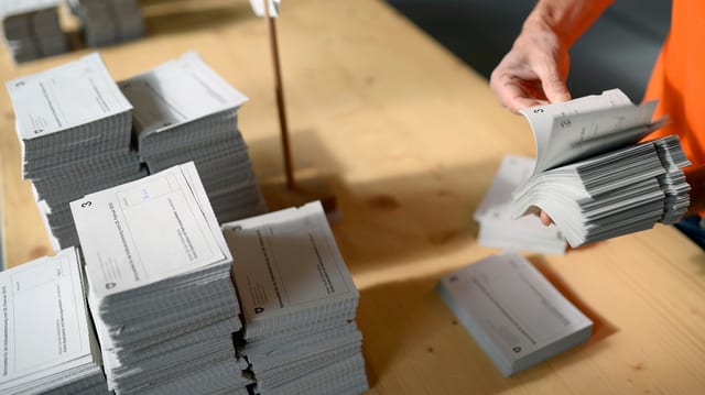 Ein Mann blättert Stimmuettel durch. Ein Mann blättert Stimmuettel durch.