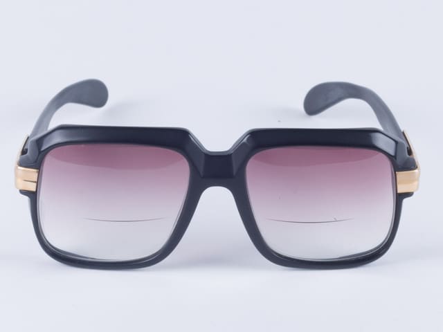 Eine Brille mit dickem, dunklen Plastikrand. Die Gläser sind leicht lila getönt. Eine Brille mit dickem, dunklen Plastikrand. Die Gläser sind leicht lila getönt.
