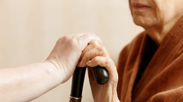 Eine Frau hät mit einer Hand einen Stock. Eine andere Person hält die Hand und den Stock. Eine Frau hät mit einer Hand einen Stock. Eine andere Person hält die Hand und den Stock.