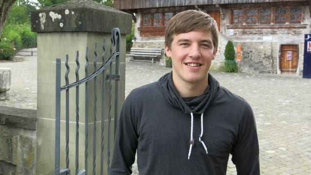 Ein junger Mann steht neben einem Tor zu einem Haus. Ein junger Mann steht neben einem Tor zu einem Haus.