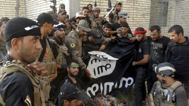 Irakische Sicherheitskräfte posieren vor heruntergenommener Fahne in Ramadi. Irakische Sicherheitskräfte posieren vor heruntergenommener Fahne in Ramadi.
