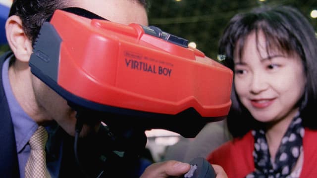 Ein Mann trägt eine rote VR-Brille mit der Aufschrift Virtual Boy. Ein Mann trägt eine rote VR-Brille mit der Aufschrift Virtual Boy.