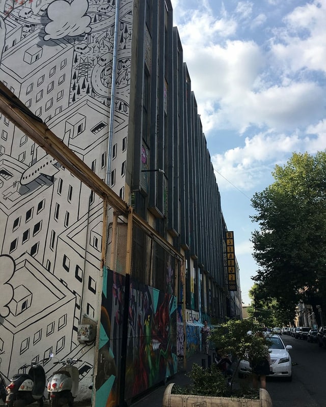 Aussenansicht eines grossen Hauses, dessen eine Wand mit einer Stadt bemalt ist. Aussenansicht eines grossen Hauses, dessen eine Wand mit einer Stadt bemalt ist.