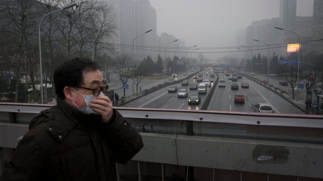 Ein Mann mit Mundschutz hastet über eine Brücke in Peking. Ein Mann mit Mundschutz hastet über eine Brücke in Peking.