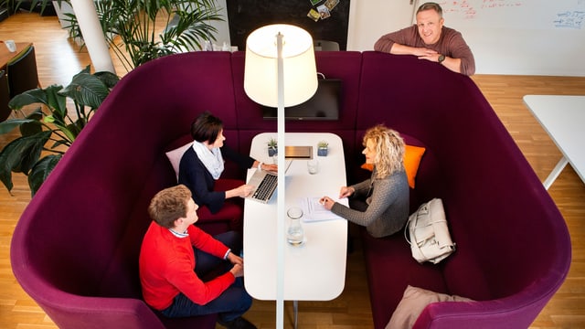 Drei Personen sitzen um einen Tisch. Drei Personen sitzen um einen Tisch.