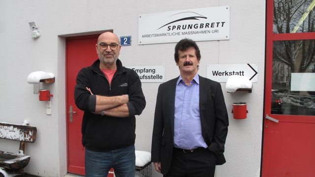 Zwei Männer stehen vor einer roten Tür. Zwei Männer stehen vor einer roten Tür.