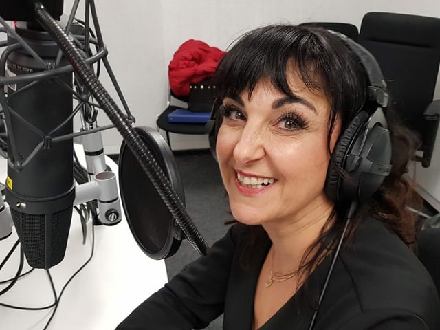 Frau sitzt im Studio hinter einem Mikrofon. Frau sitzt im Studio hinter einem Mikrofon.