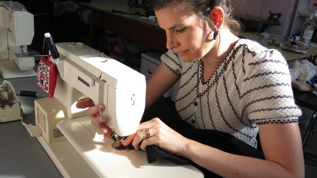 Frau sitzt an Nähmaschine. Frau sitzt an Nähmaschine.