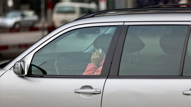 Eine Frau telefoniert mit ihrem Handy am Steuer ihres Autos. Eine Frau telefoniert mit ihrem Handy am Steuer ihres Autos.