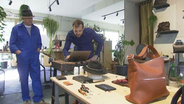 Zwei Männer in einem Geschäft. Auf einem Tisch stehen Ledertaschen. Zwei Männer in einem Geschäft. Auf einem Tisch stehen Ledertaschen.