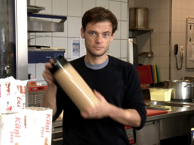 Ein Mann schaut in die Kamera, während er einen Behälter mit Flüssigkeit schüttelt. Ein Mann schaut in die Kamera, während er einen Behälter mit Flüssigkeit schüttelt.