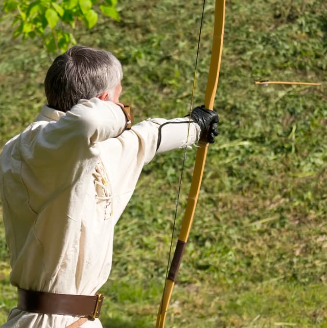 Mann zieht an einem traditionellen Bogen ohne technischen Hilfsmittel. Mann zieht an einem traditionellen Bogen ohne technischen Hilfsmittel.