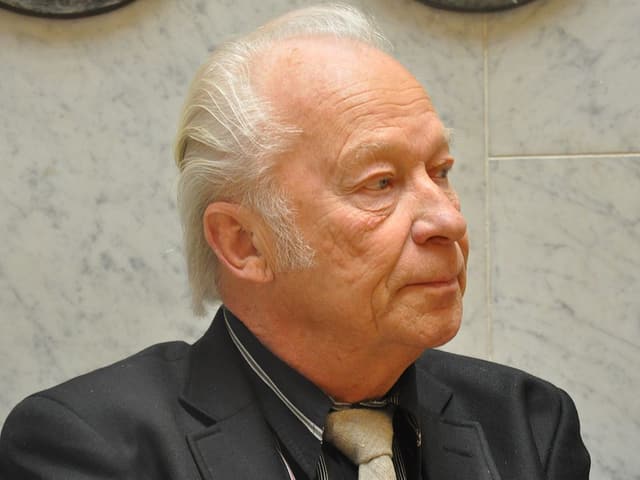 Aulis Sallinen trägt eine Krawatte und hat graues Haar. Aulis Sallinen trägt eine Krawatte und hat graues Haar.