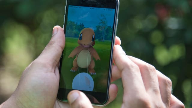 Grossaufnahme eines Handys mit Pokémon auf dem Display, von einem Spieler gehalten Grossaufnahme eines Handys mit Pokémon auf dem Display, von einem Spieler gehalten