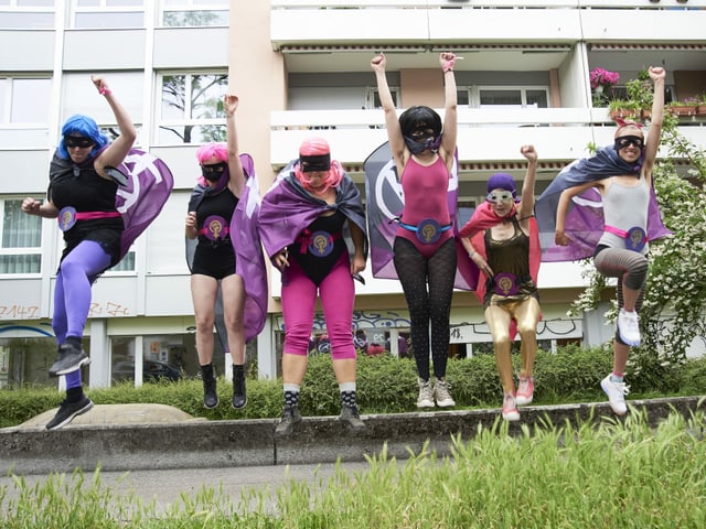 Eine Gruppe Mädchen in Superheldinnen-Kostümen springt in die Luft. Eine Gruppe Mädchen in Superheldinnen-Kostümen springt in die Luft.