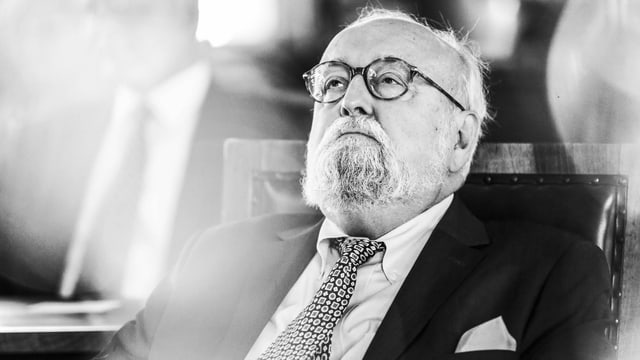 Ein älterer Mann in Anzug, mit Brille sitzt in einem Konzert und starrt nachdenklich an die Decke. Ein älterer Mann in Anzug, mit Brille sitzt in einem Konzert und starrt nachdenklich an die Decke.