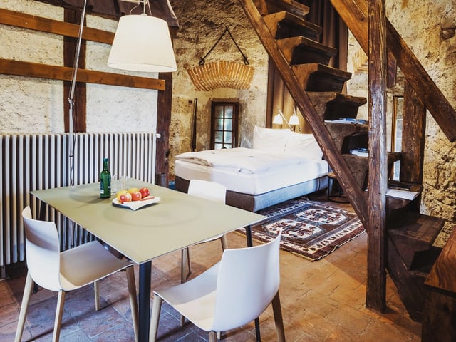 Ein Zimmer mit Tisch und Bett in einem alten Gebäude Ein Zimmer mit Tisch und Bett in einem alten Gebäude