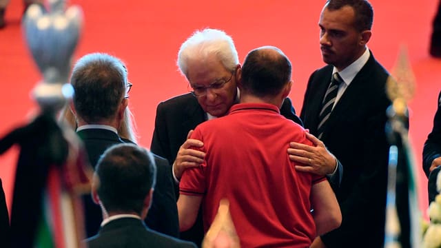 Mann mit weissen Haaren (Mattarella) umarmt anderen Mann. Mann mit weissen Haaren (Mattarella) umarmt anderen Mann.