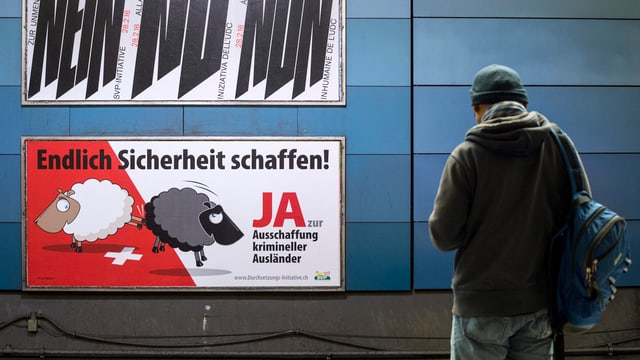 Ein Mann vor einem SVP-Plakat zur Durchsetzungsinitiative. Ein Mann vor einem SVP-Plakat zur Durchsetzungsinitiative.
