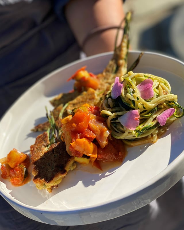 Wildgemüse-Piccata mit Tomatensalsa und Zucchetti-Spaghetti auf weissem Teller Wildgemüse-Piccata mit Tomatensalsa und Zucchetti-Spaghetti auf weissem Teller