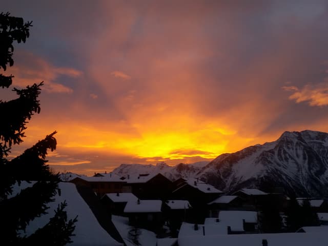 Die Sonne scheint durch Wolken und verfärbt diese gelblich und rötlich.