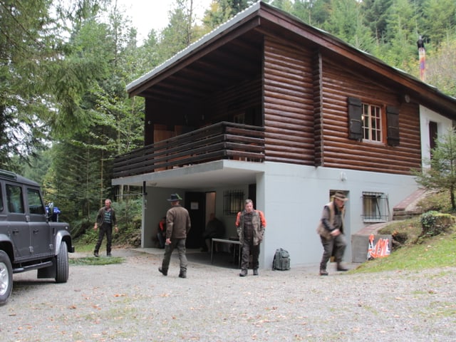 Jäger in grüner Bekleidung vor der Jagdhütte.