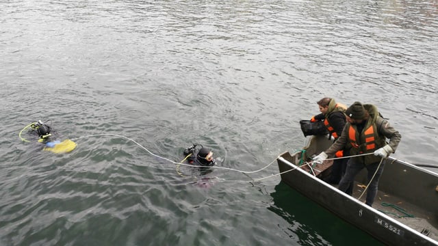 Zwei Taucher im Wasser, zwei Jugendliche mit Schwimmwesten im Weidling Zwei Taucher im Wasser, zwei Jugendliche mit Schwimmwesten im Weidling