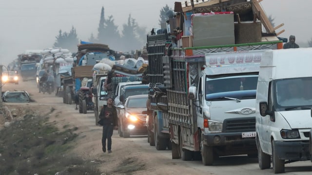 Kolonne mit Autos, Transportern und LKWs, alle voll beladen mit Möbeln und Haushaltswaren. Kolonne mit Autos, Transportern und LKWs, alle voll beladen mit Möbeln und Haushaltswaren.