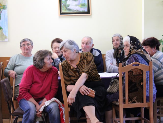 Alte Menschen warten im Saal.