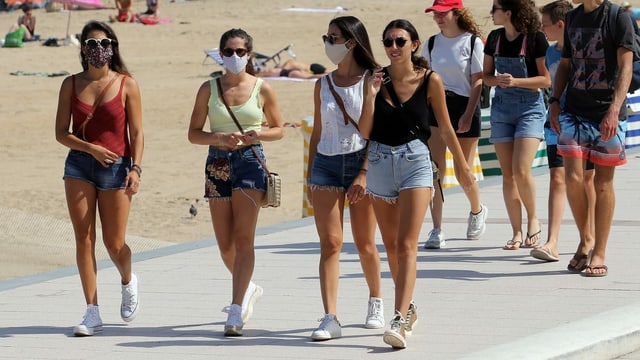 Junge Leute mit und ohne Masken laufen am Strand. Junge Leute mit und ohne Masken laufen am Strand.